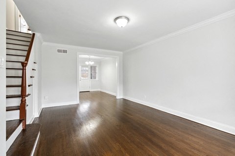 an empty living room with white walls and wooden floors and a staircase