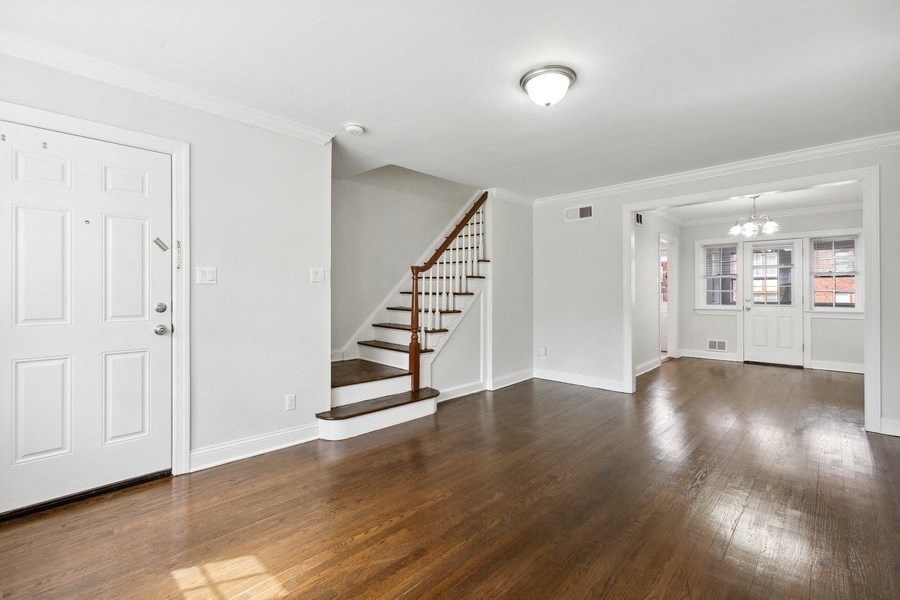 the living room and entryway of a house with white walls and wood floors