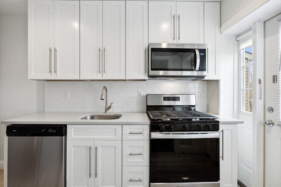 a kitchen with white cabinets and a stove and a microwave