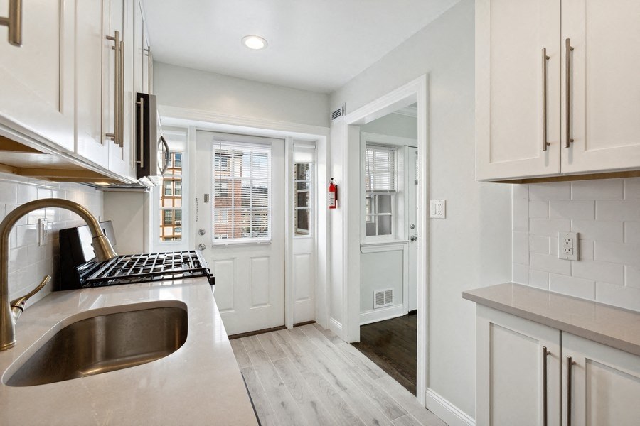 a kitchen with white cabinets and a sink and a doorway