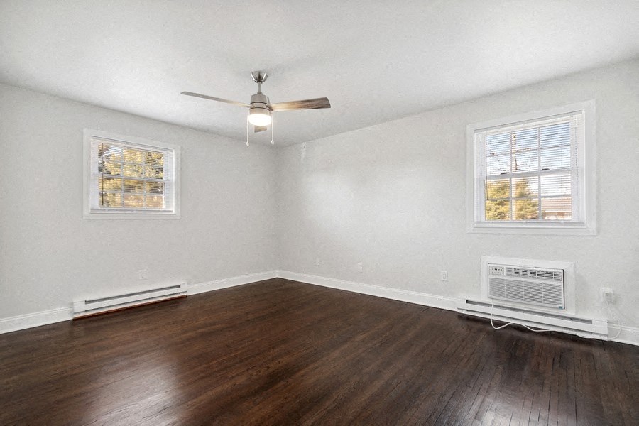 an empty living room with wood floors and a ceiling fan