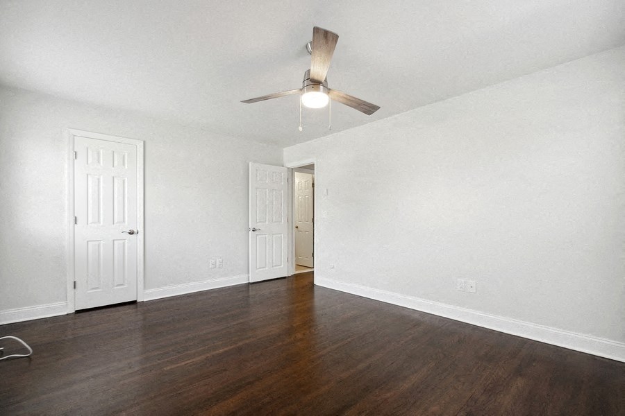 an empty living room with wood flooring and a ceiling fan