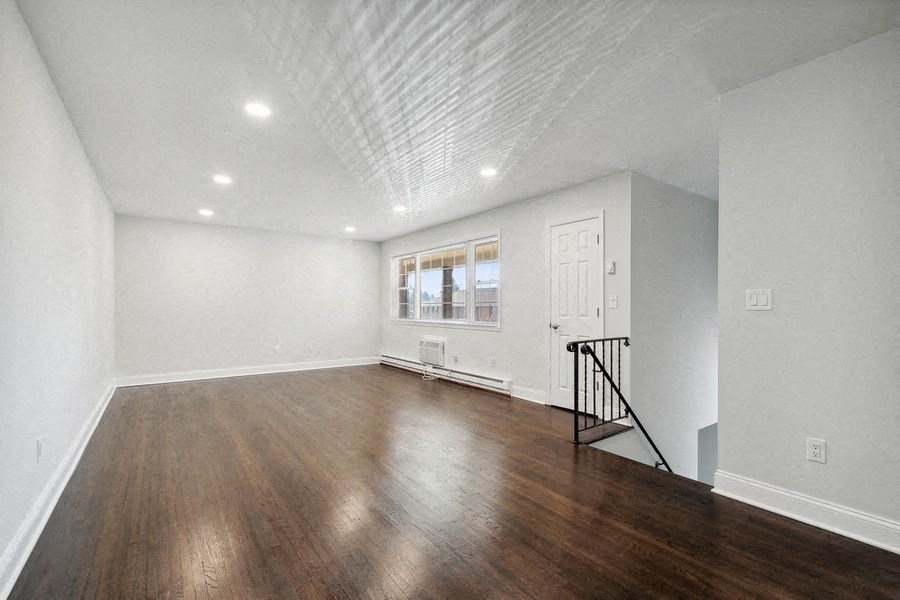 an empty living room with wood floors and white walls