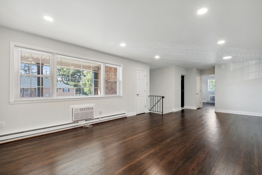 an empty living room with wood floors and a large window