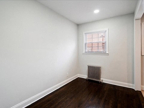 A room with a window and a radiator on the floor.