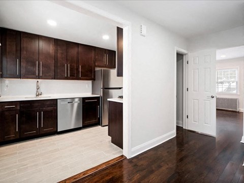 A kitchen with dark brown cabinets and a white dishwasher.