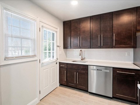 A kitchen with brown cabinets and a stainless steel dishwasher.