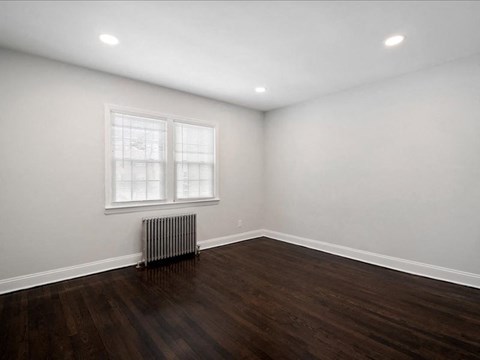 A room with a window and a radiator on the floor.