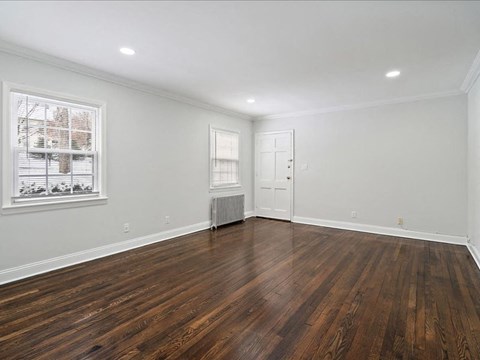 A room with wooden floors and a window with blinds.
