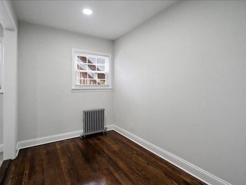 A room with wooden floors and a window with blinds.