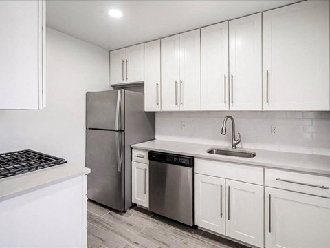 A kitchen with white cabinets and a stainless steel refrigerator.