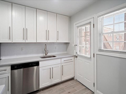 A kitchen with white cabinets and a stainless steel dishwasher.