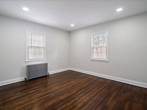 A room with wooden floors and two windows.