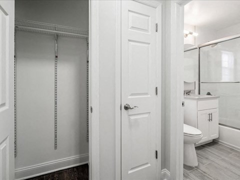A white bathroom with a toilet, sink, and a walk-in closet.