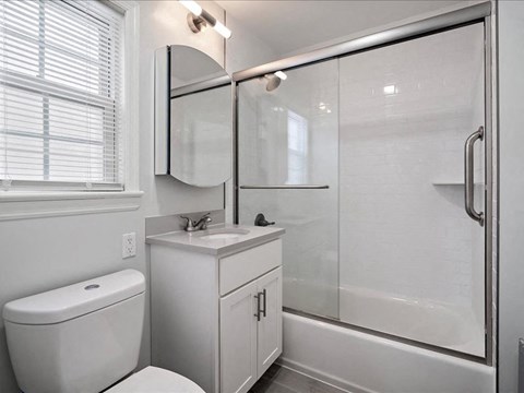 A white bathroom with a toilet, sink, and shower.