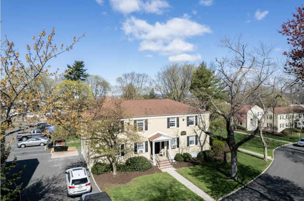 an aerial view of a yellow house with cars parked in front