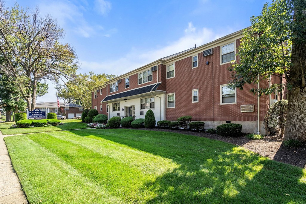 exterior view of a brick apartment building with lawn and trees