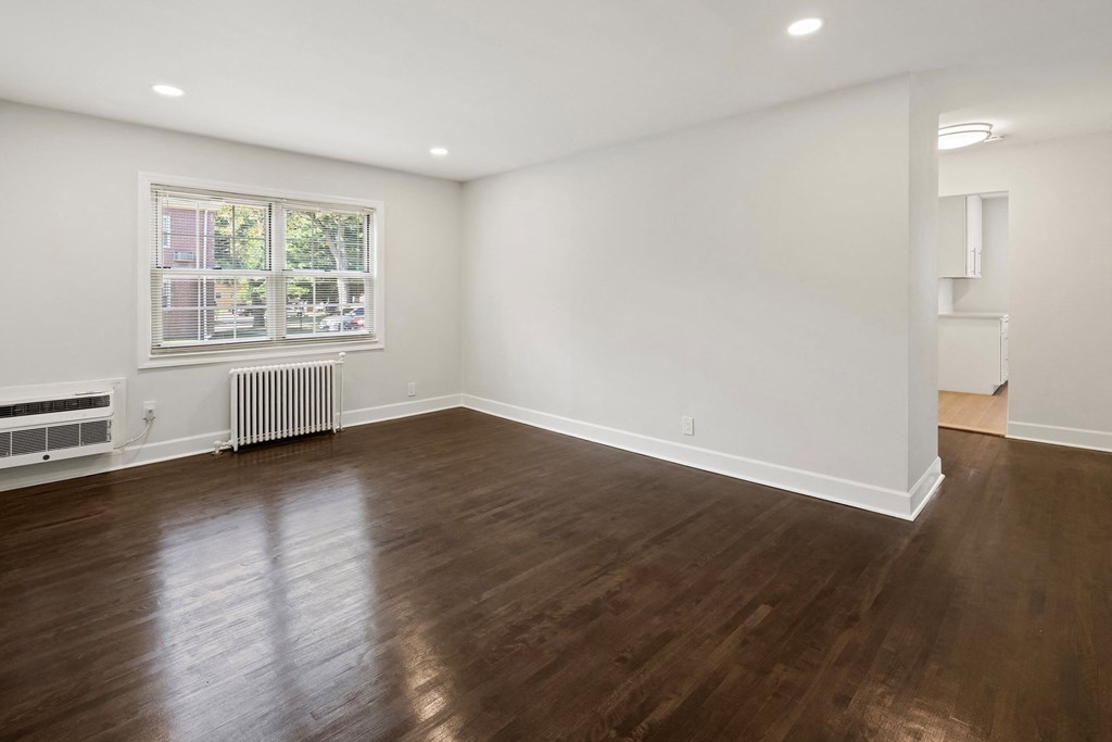 a living room with wood floors and white walls and a window