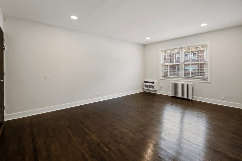 a living room with white walls and wood floors and a window