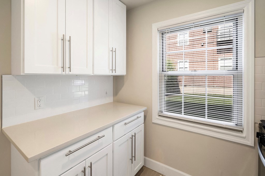 a small kitchen with white cabinets and a window