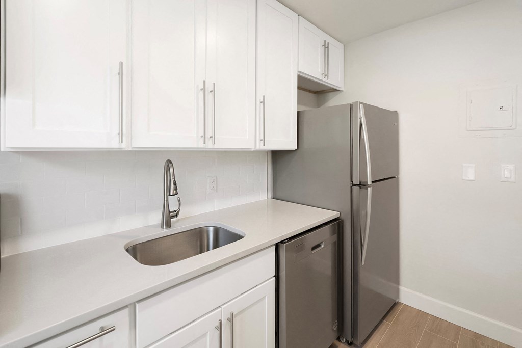 an empty kitchen with white cabinets and a stainless steel refrigerator