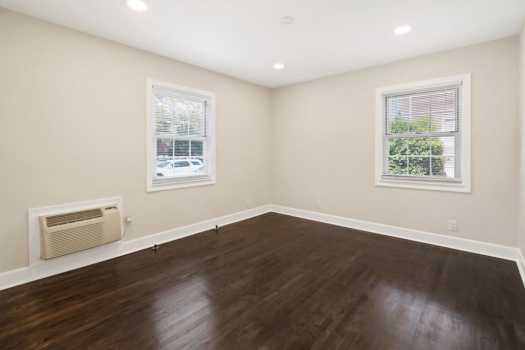 an empty living room with wood flooring and two windows