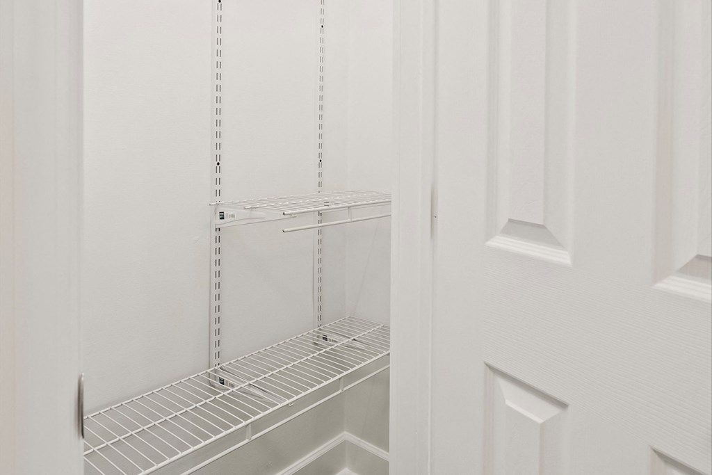 a white closet with white shelves and a white door