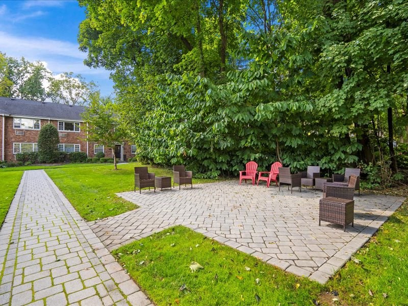 a brick patio with chairs and a brick building in the background