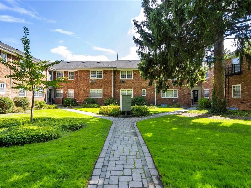 a brick building with a walkway and grass in front of it