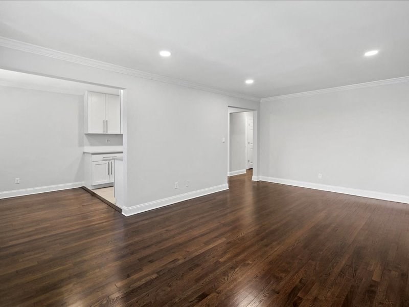 a living room and kitchen with wood floors and white walls