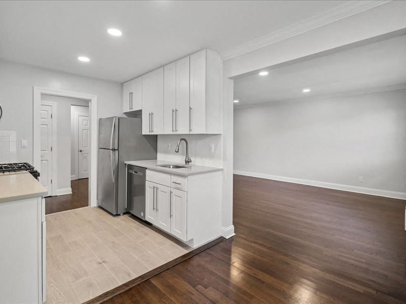 an empty kitchen with white cabinets and a stainless steel refrigerator