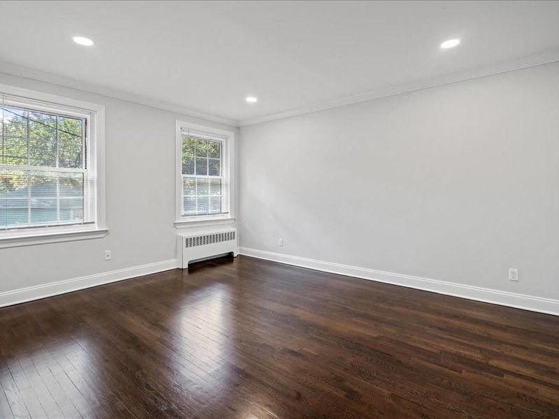 an empty living room with wooden floors and a window