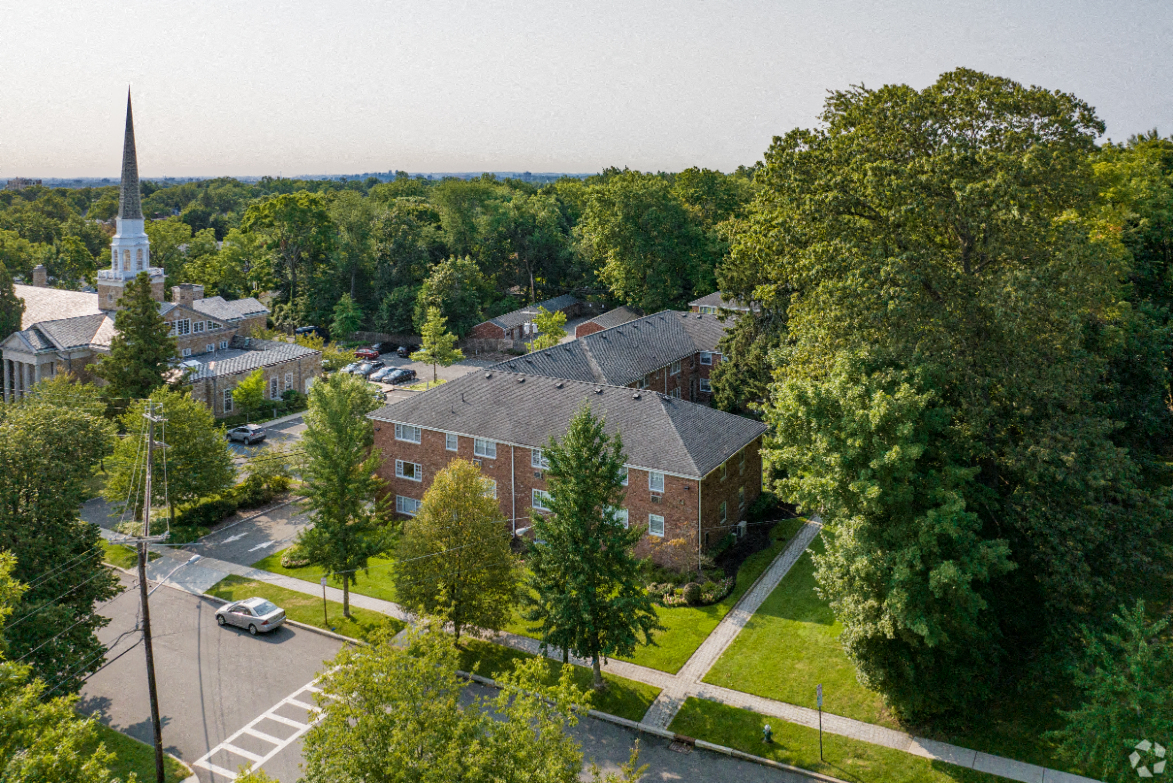 an aerial view of a brick building with a church in the background