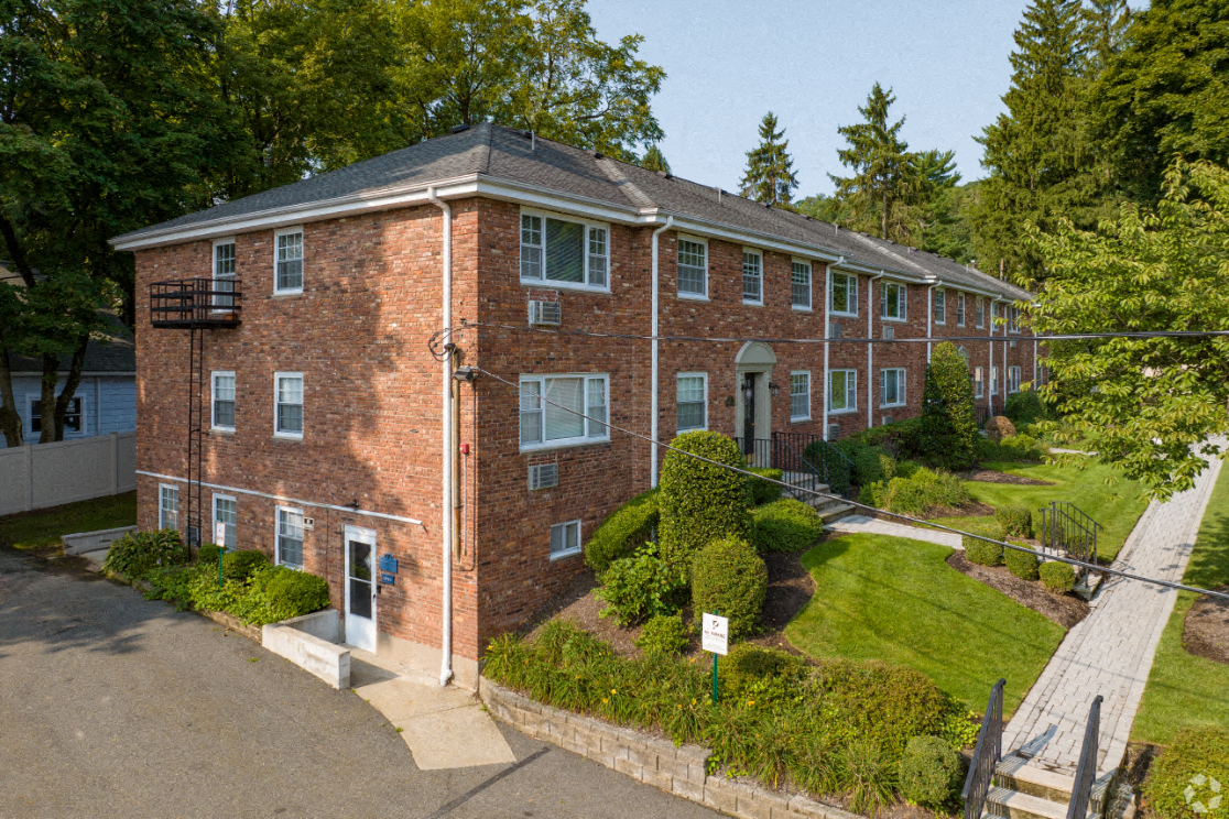 a red brick apartment building with green grass and trees