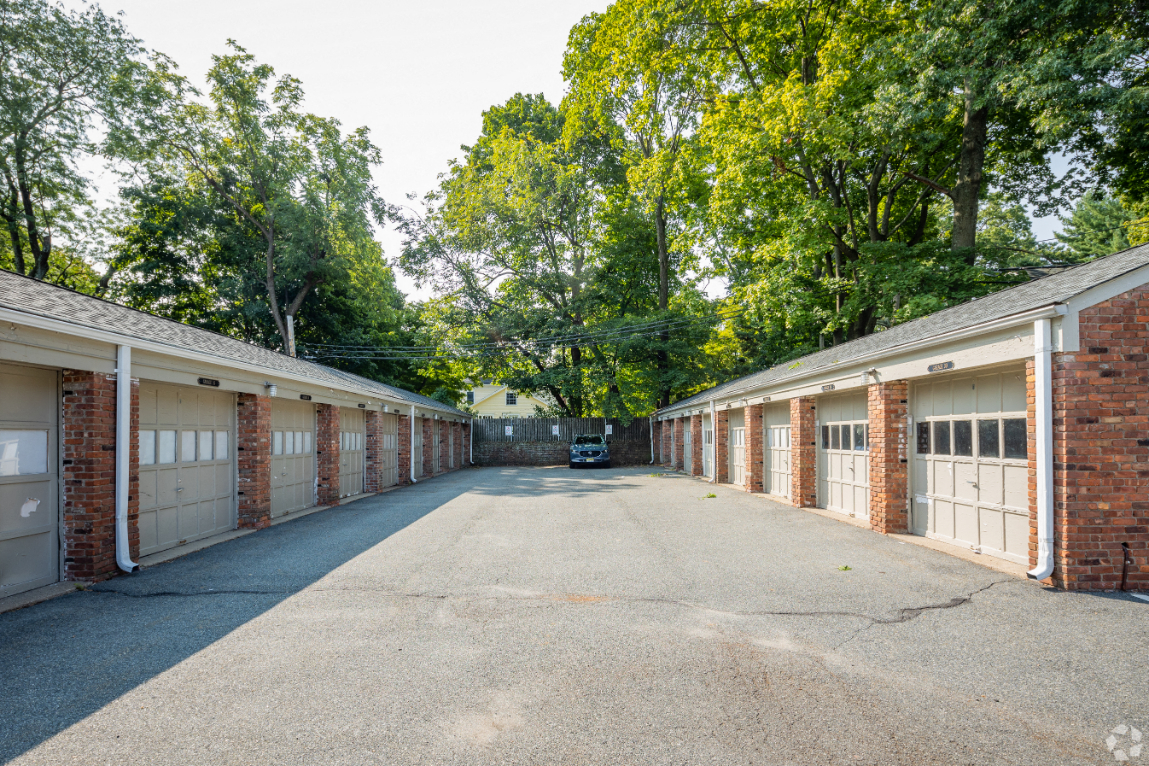 an empty parking lot with many garage doors and brick buildings
