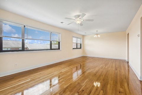 an empty living room with a large window and a ceiling fan