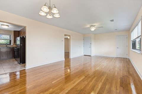 an empty living room and kitchen with wood floors and white walls