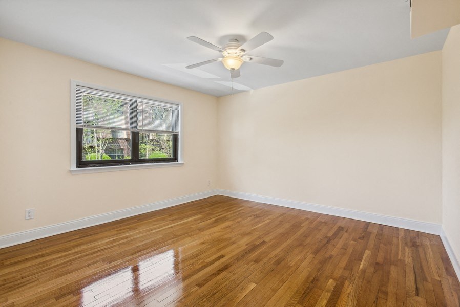 an empty living room with a ceiling fan and a window