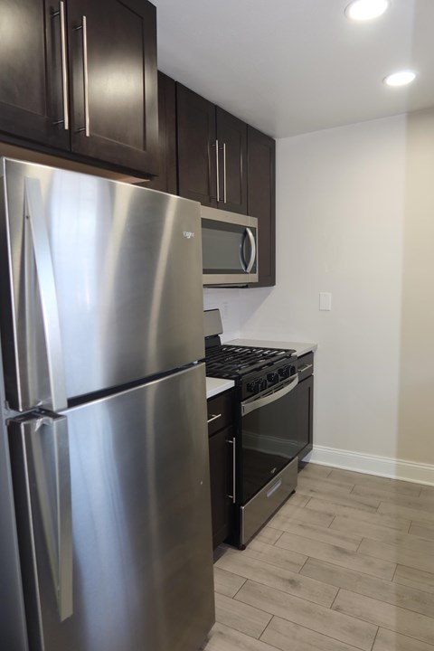 A stainless steel refrigerator is in a kitchen with wooden cabinets.