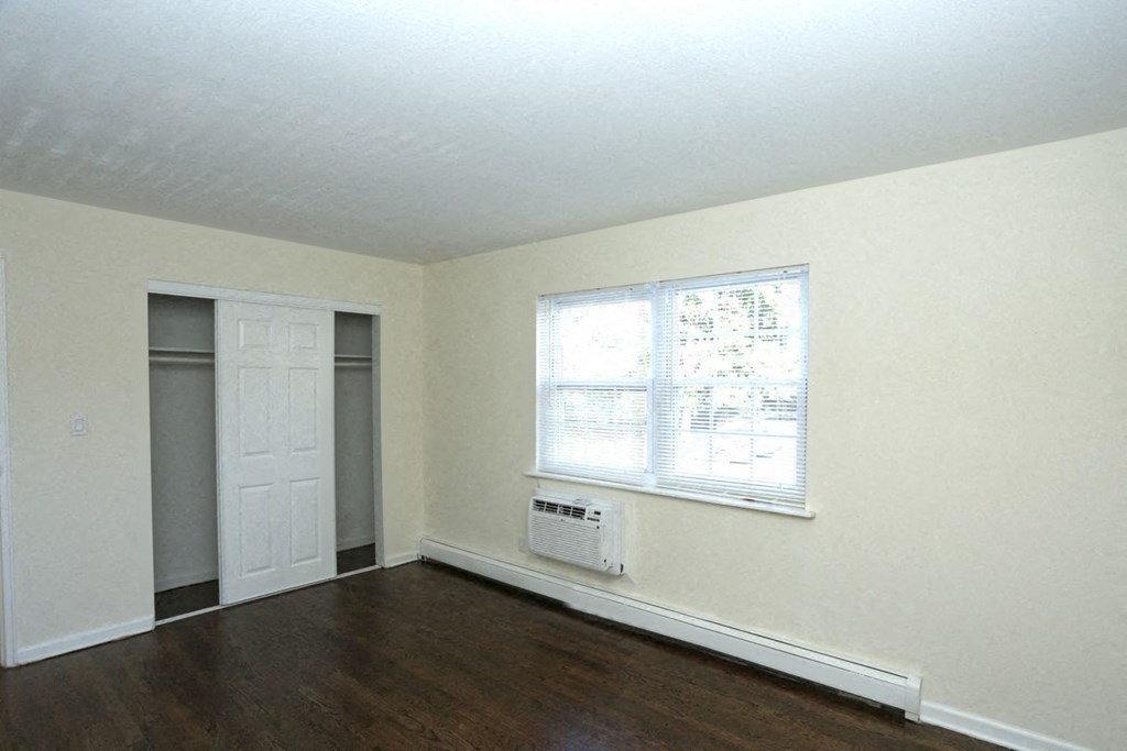 an empty living room with wood floors and a window