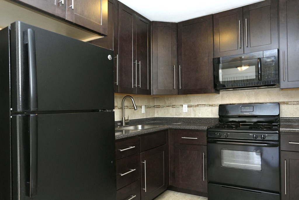 a kitchen with black appliances and dark wood cabinets