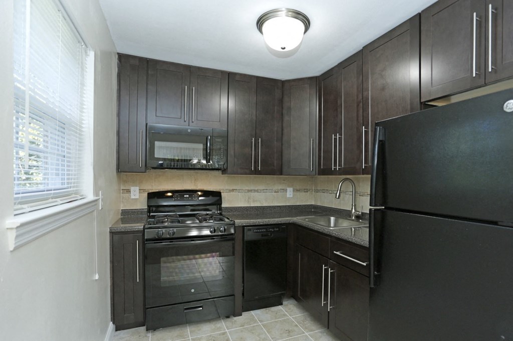 a kitchen with black appliances and dark wood cabinets
