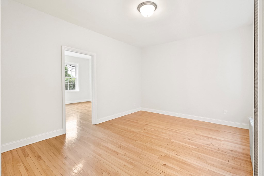 a living room with hardwood floors and white walls and a window