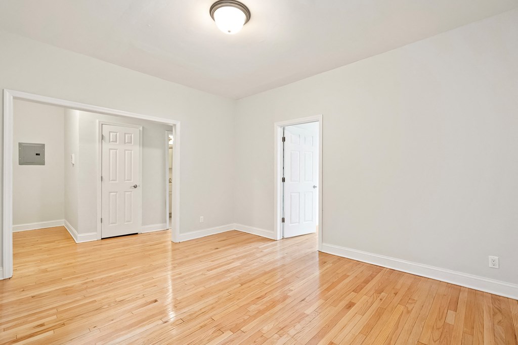an empty living room with wood floors and white walls