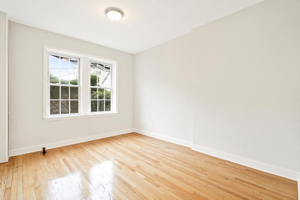 an empty living room with wood floors and a window