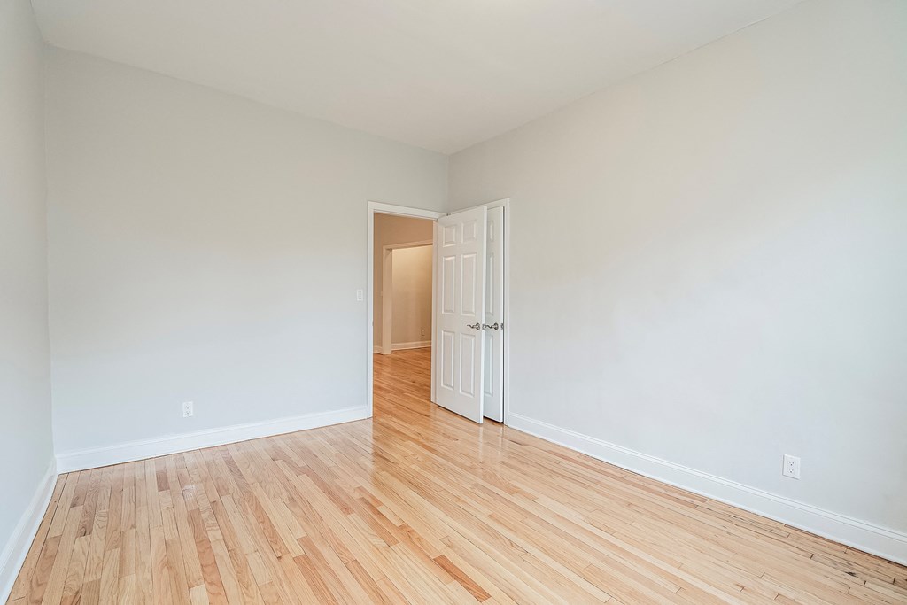 an empty living room with wood floors and white walls