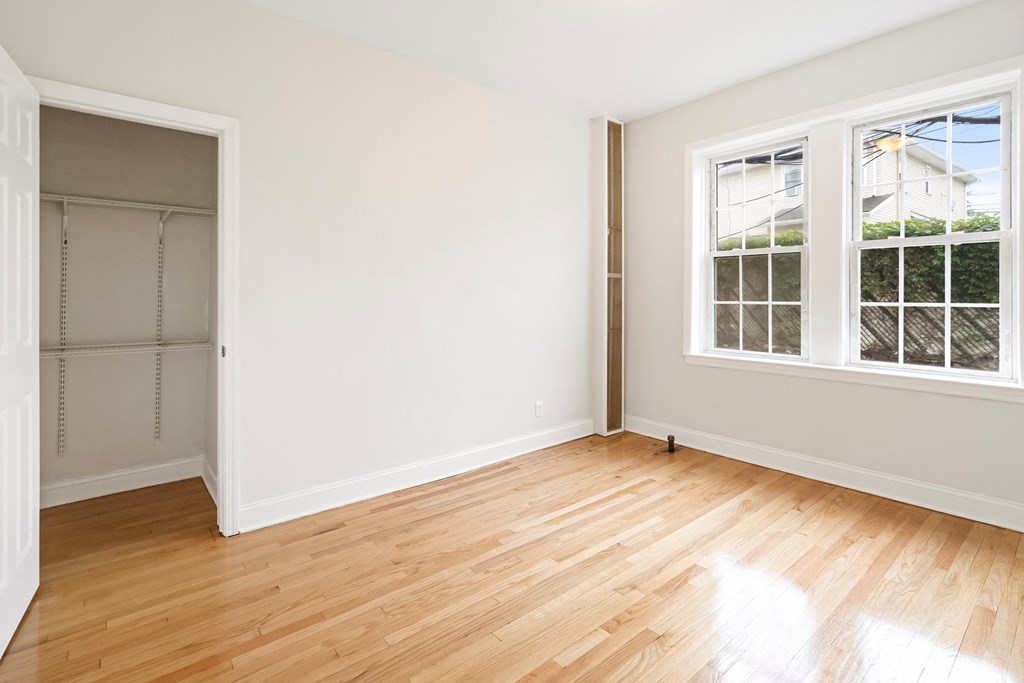 an empty room with white walls and wood floors and a closet