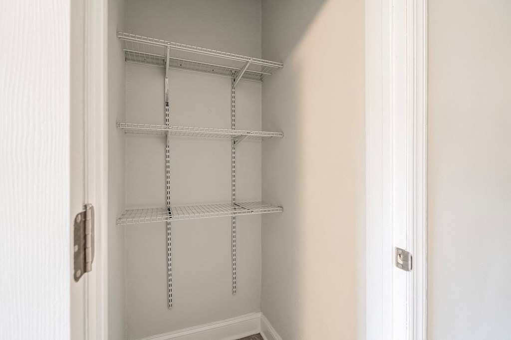 an empty closet with white shelving and a white door