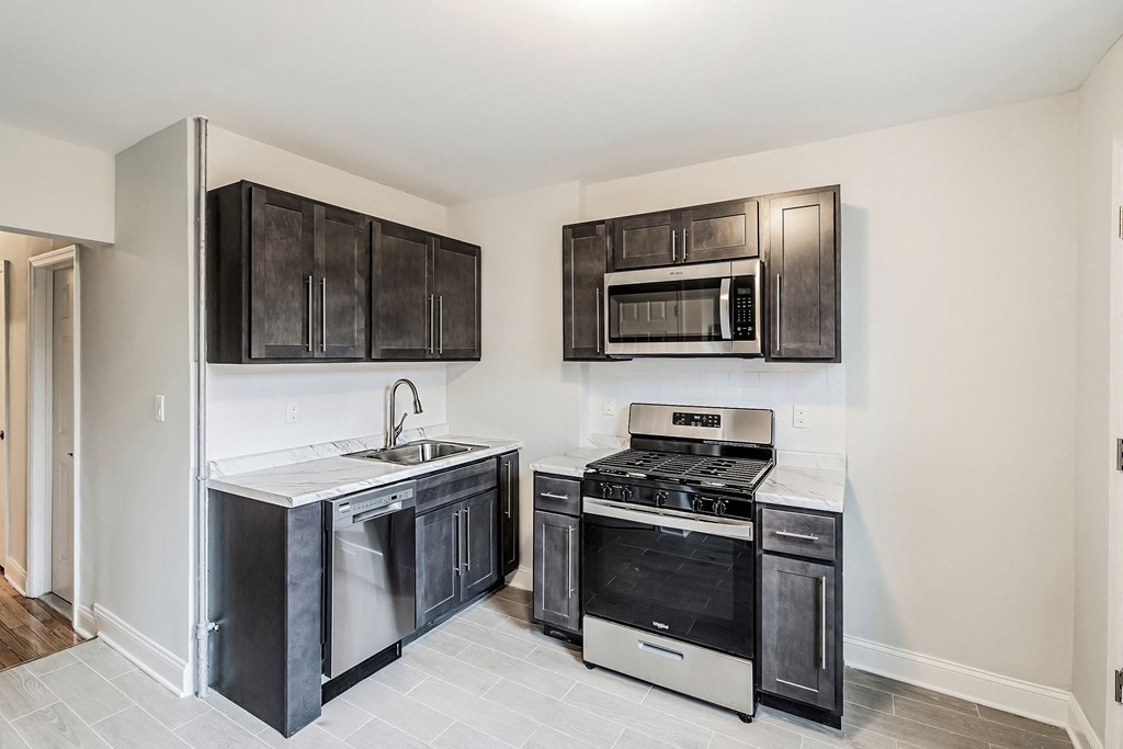 an empty kitchen with black cabinets and stainless steel appliances