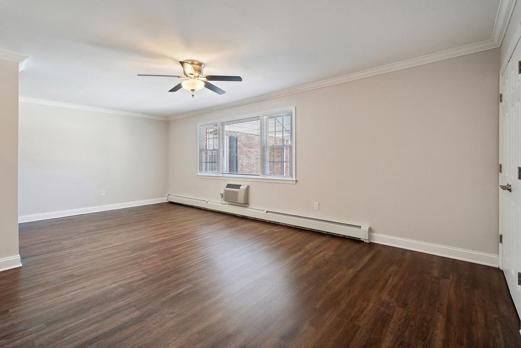 A room with a ceiling fan and a window with a view of a building outside.